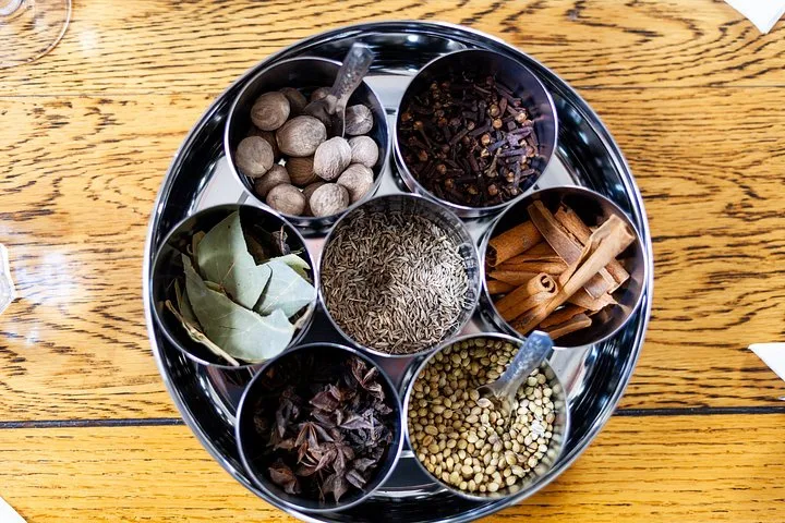 A tin of whole spices: cinnamon, cloves, cardamom and peppercorns