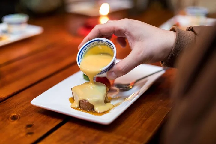 Custard poured over a warm pudding on a white plate