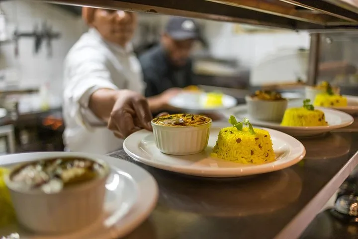 Plates of yellow rice and baked dishes lined up at a kitchen pass