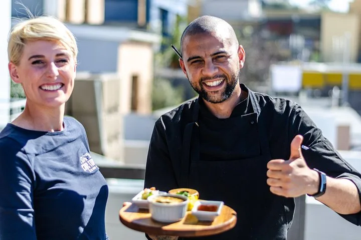 A guide and a chef holding up a tasting board